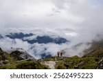 hikers on steep winding trail through green mountains and low clouds