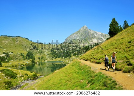 Hikers on a trip in Neouvielle national nature reserve, Lac du Milieu, French Pyrenees. Beautiful summer mountain landscape in the sunny day.