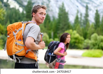 Hikers - people hiking, man looking at mountain nature landscape scenic with woman in background. Happy multicultural young couple in Yosemite National Park, California, USA - Powered by Shutterstock