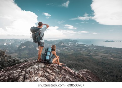 Hikers stand on top of a mountain and enjoy valley view