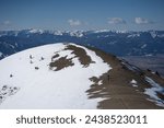 Hikers traveling on a ridgeline in the Bridger Mountain Range near Bozeman, Montana with the Gallatin mountains in the background