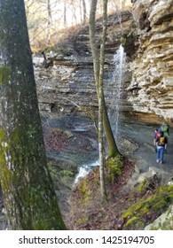 Hikers Trek A Waterfall On A Trail At Devil's Den State Park In Arkansas