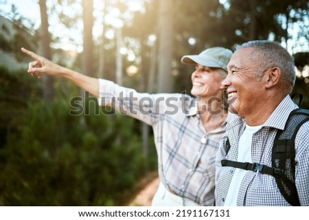 Hiking, adventure and freedom with a senior couple enjoying and exploring the forest or woods and bonding together. Happy, carefree and exploring retired man and woman looking at the views outdoors