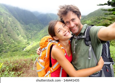 Hiking couple - Active young couple in love. Couple taking self-portrait picture on hike. Man and woman hiker trekking on Waihee ridge trail, Maui, USA. Happy romantic interracial couple. - Powered by Shutterstock