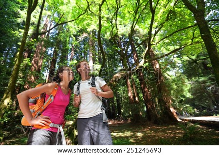 Hiking couple in forest Redwoods, San Francisco. Hiker couple walking among Redwood trees near San Francisco, California, USA. Multiracial couple, young Asian woman and Caucasian man.
