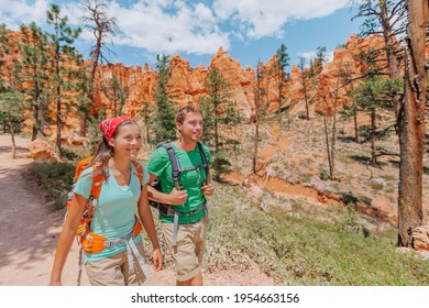 Hiking Couple Hikers Walking Smiling Happy In Summer Mountain Nature. Interracial Couple Asian Woman And Caucasian Man In Bryce Canyon National Park Landscape, Utah, United States.