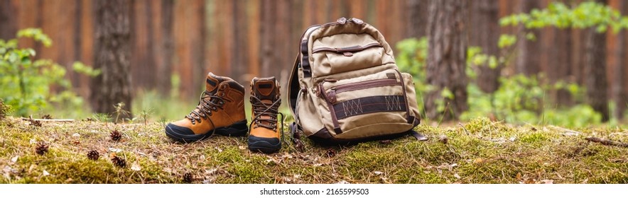 Wanderausrüstung im Wald. Rucksack- und Lederknöchelstiefel. Panoramasicht auf Kopienraum