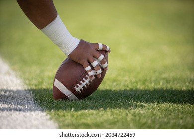 Hiking the football in a football game. Focus on the hands and the details of the football.	
