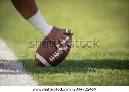 Hiking the football in a football game. Focus on the hands and the details of the football.	
