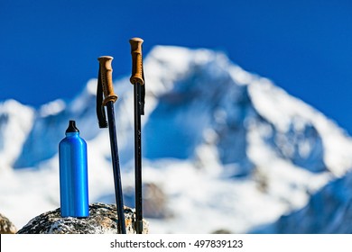 Hiking Gear Over Himalaya Mountains Background. Travel Equipment, Trekking Stick And Water Bottle In Inspirational High Himalayas Landscape Over Blue Sky In Nepal.