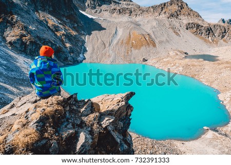 Hiking girl looks at the lake from a height. Beautiful turquoise lake in the mountains.
