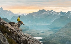 
Hiking In The Incredible Jurassic Wild Landscape Of Green Mountains, Among Glaciers And Volcanoes. Adventurous Man Is On Top Of The Mountain And Enjoying The Beautiful View During A Vibrant Sunset