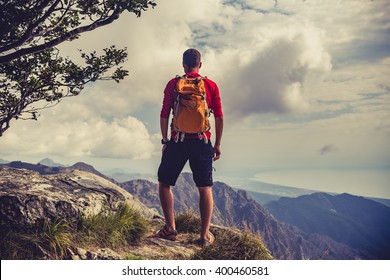 Hiking Man, Climber Or Trail Runner In Mountains, Inspirational Landscape. Motivated Hiker With Backpack Looking At Beautiful View. Trekking, Travel And Tourism Concept. Fitness And Healthy Lifestyle.