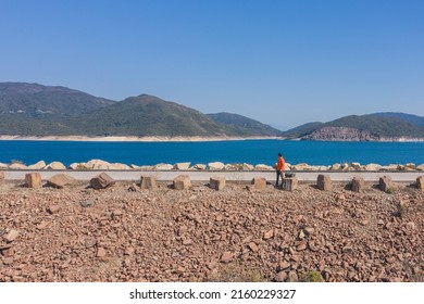 Hiking Man Standing On Dam Of High Island Reservoir, Sai Kung, Hong Kong In Autumn