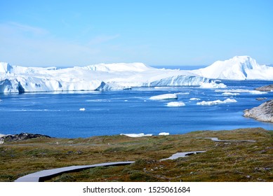 hiking on boardwalk in Ilulissat Greenland - beautiful icebergs in the Disko Bay / Baffin Bay - nature, rocks, blue sky, ice sea - Powered by Shutterstock