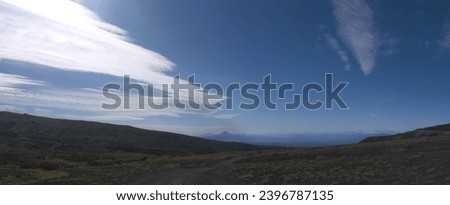 Hiking on Kamchatka, panoramic view on valley and distant tourist group on the trail, Avachinskaya bay with Vilyuchinsky volcano with dramatic cirrus clouds on blue sky background