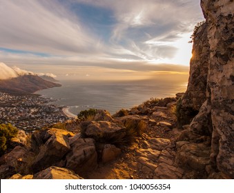 Hiking Path Lit Up By Sunset Light, Ocean And Mountains With Clouds In The Background, Lions Head Mountain In Cape Town