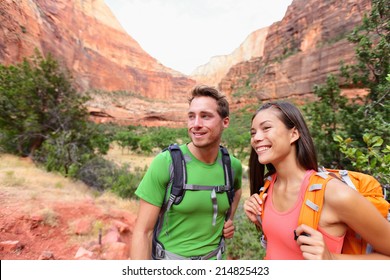 Hiking People - Hiker Couple On Hike Outdoors Enjoying Active Lifestyle In Beautiful Mountain Landscape In Zion National Park. Multiracial Asian Woman And Caucasian Man In Utah, USA.