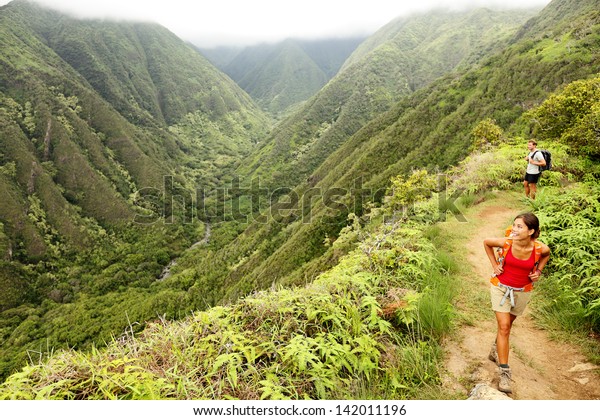 ハワイ ワイヒー リッジ トレイル 米国マウイ 若い女性と男性のハイカーが 山の中の美しいハワイの森の自然の風景を歩いています 前景にアジアの女性のハイカー の写真素材 今すぐ編集