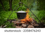 Hiking pot, Bowler in the bonfire. Fish soup boils in cauldron at the stake. Traveling, tourism, picnic cooking, cooking at the stake in a cauldron, fire and smoke