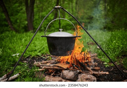 Hiking pot, Bowler in the bonfire. Fish soup boils in cauldron at the stake. Traveling, tourism, picnic cooking, cooking at the stake in a cauldron, fire and smoke