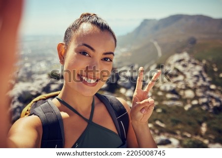 Hiking selfie, happy woman and fitness in nature on a mountain for exercise, travel and trekking adventure during summer. Face, smile and peace sign female tourist exploring outdoors with a backpack