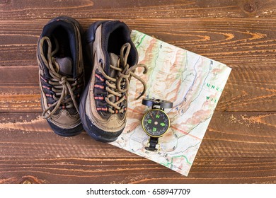 Hiking Shoes With Topo Map And Compass On A Wood Background.