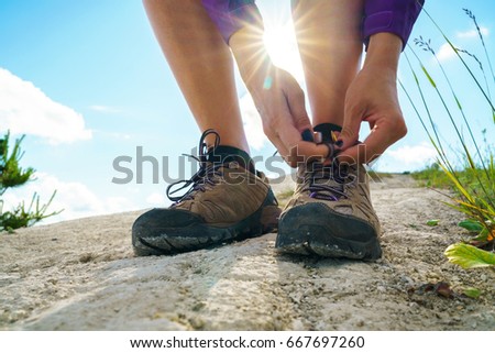 Hiking shoes - woman tying shoe laces. Closeup of female tourist getting ready for hiking