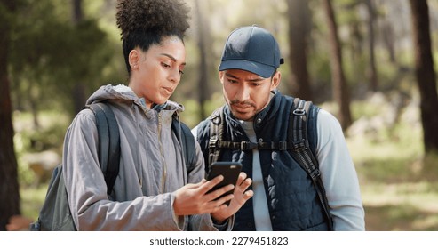 Hiking, smartphone and travel couple with location search, online travel guide or nature journey planning together in a forest on 5g network. Backpack trekking people using phone mobile app in woods - Powered by Shutterstock