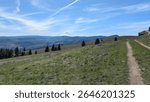 Hiking trail winding along the ridge of a wide green meadow curving into the massive valley of the Columbia River Valley on a beautiful sunny day. 