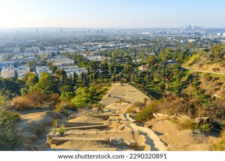 Hiking with the view: Los Angeles skyline as seen from the scenic vista point at Runyon Canyon Park on a sunny day.