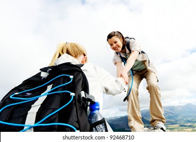 Hiking Woman Helps Her Friend Climb Onto The Rock, Outdoor Lifestyle Concept