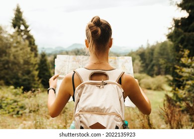 Hiking young woman traveler with backpack checks map to find directions in wilderness area, real explorer. Travel Concept - Powered by Shutterstock