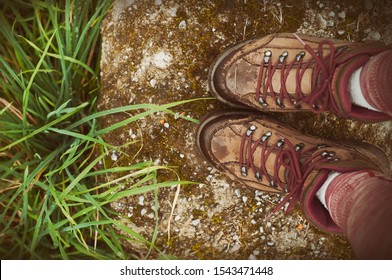 Hiking.Woman Legs With Hiking Boots On The Mountain Path, Top View. Stones And Green Grass