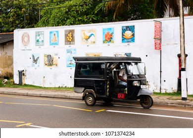 Hikkaduwa, Sri-Lanka, April 4, 2018: The Old Architecture - Post Office And White Fence Aroud With National Lankas Postal Stamps. Street View With Black Tuk-tuk And Driver.