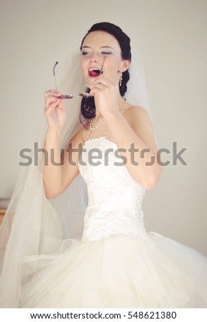 Hilarious bride. Playful model in a wedding dress having fun, fooling around. Indoor photo.