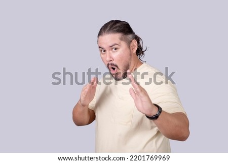 Hilarious and funny scene of a stocky man threatening to use kung fu to defend himself. Probably pretending or acting for fun. Isolated on a gray background.