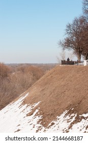 A Hill Covered With Melting Snow Going Up To The Observation Deck With A Silhouette Of A Man Standing On Top. A Leafless Tree Is Nearby And Lots Of Them In The Distance. Morning Spring Sunny Day