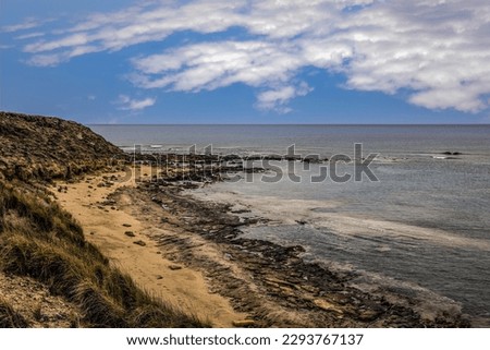 Hill Top View of Stone Beach with Yellow Sand, next to Fishing Shelter with Light Breeze on Mediterranean Sea Under Blue Sky with Clouds (Akrotiri Peninsula, Limassol, Cyprus, Great Britain Territory)