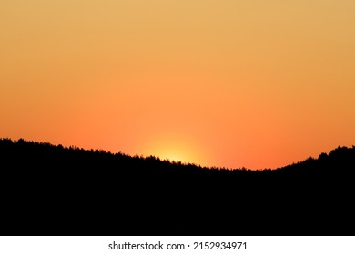 Hills Against The Backdrop Of Sunset, Uneven Skyline In The Form Of A Silhouette. Evening Time