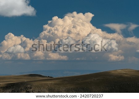 Hills and large cumulonimbus clouds