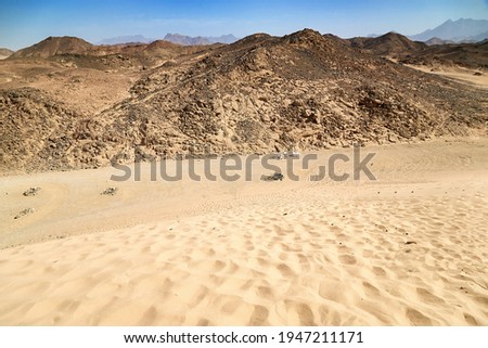 Hillside with rocks in dry desert. Egypt hot lifeless sand and rock mountain and blue sky in summer sunny day. Travel and tourism concept.
