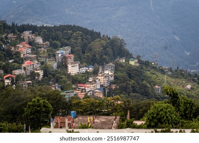 A hillside scene featuring clusters of colorful houses amidst lush greenery, set against a backdrop of mountains and fading blue skies. It's a tranquil, picturesque location. - Powered by Shutterstock