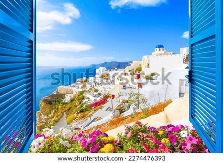 Hillside view through an open window with blue shutters of the blue dome church, caldera, sea and white village of Oia on the island of Santorini, Greece.