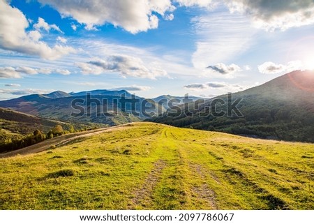 hilltop on the background of a mountain range with blue sky and sun rays on a teali summer day. Mountain landscape. 
