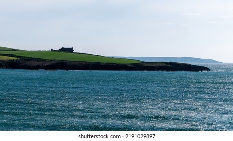 The Hilly Coast Of The Atlantic Ocean In The South Of Ireland. Beautiful Seascape, Sunny Warm Weather. A Beautiful Place On The Seashore. The Blue Water Of The Celtic Sea. Green Field Near Water