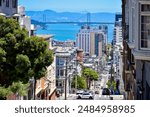 A Hilly street in San Francisco with the Oakland Bay Bridge 