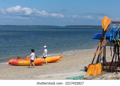 Hilton Head Island, SC USA - Oct 10 2022:  Two Young Boys Explore Orange Kayaks On A Bright Sunny Day With Blue Sky Overhead