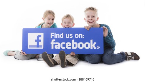 HILVERSUM, NETHERLANDS - APRIL 11, 2014: Sitting Little Kids Isolated On White In A Studio Holding A Find Us On Facebook Sign.