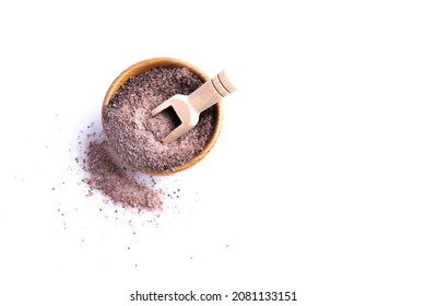 Himalayan black ground salt in a wooden cup on a white background.